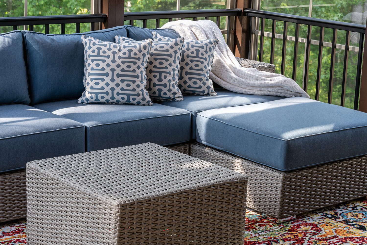 Outdoor furniture with large blue cushions and white and blue throw pillows.
