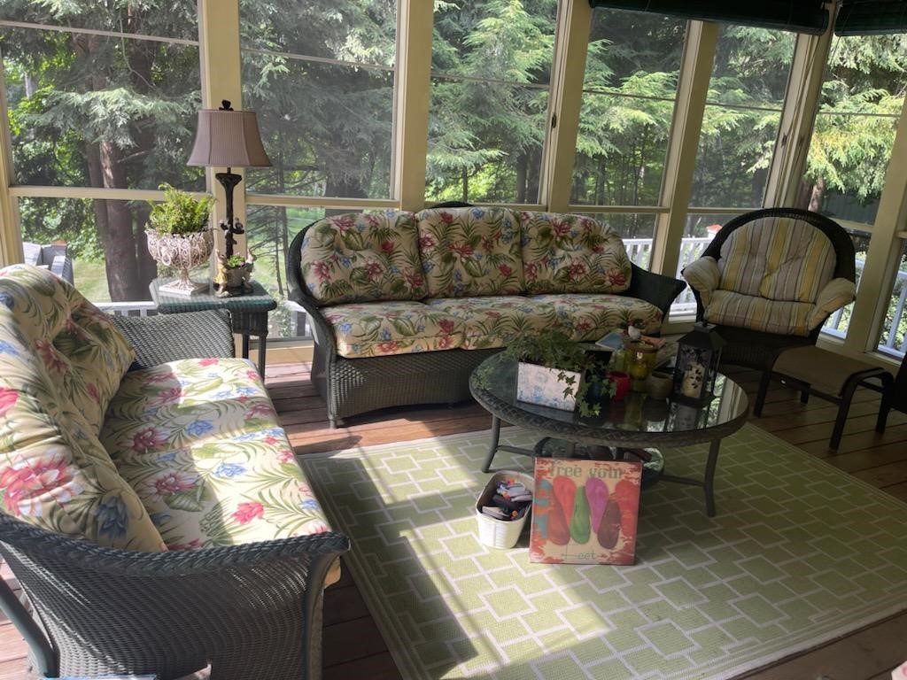 Furniture in an indoor, screened-in sitting room.